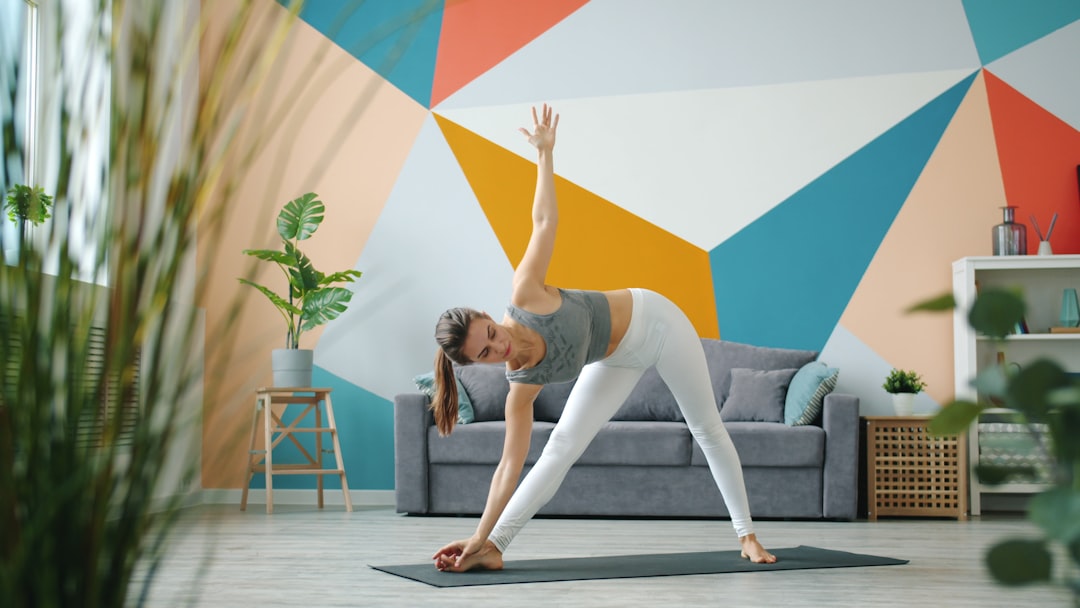 Mulher praticando a postura do triângulo no yoga em casa.