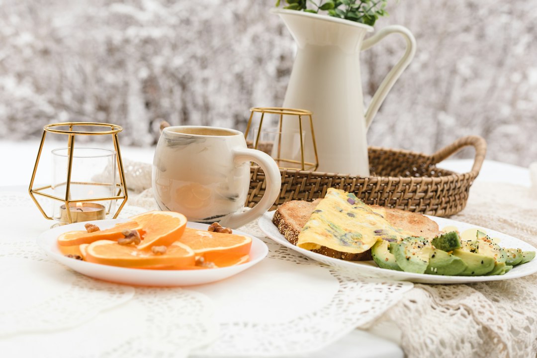 frutas fatiadas em um prato de cerâmica branca ao lado de uma caneca de cerâmica branca com café